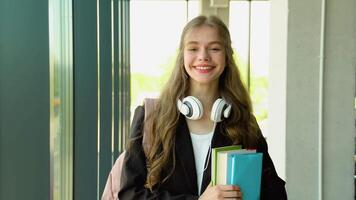 Portrait of an college girl student with books in hands in the university building. Back to school video