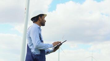 Indian worker checks Wind Turbine system with a tablet. Alternative Energy. Wind farm video