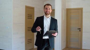 Real estate agent with keys sells new wooden house. Concept of modular houses. Space for text video
