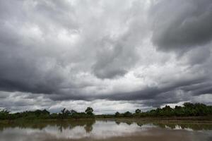 The rain clouds that are forming above the fields are rain clouds caused by storms that are resting moisture into the seasonal areas. The sky background is full of black clouds from thunderstorm. photo