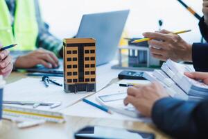 A team of engineers and architects discuss house plan design and estimate construction prices to suit the construction budget. Checking blueprints and documents with a team of engineers and architects photo