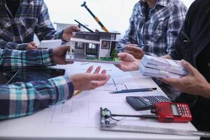 team of engineers and architects discuss house plan design and estimate construction prices to suit the construction budget. Checking blueprints and documents with a team of engineers and architects photo
