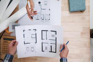 A team of engineers and architects discuss house plan design and estimate construction prices to suit the construction budget. Checking blueprints and documents with a team of engineers and architects photo
