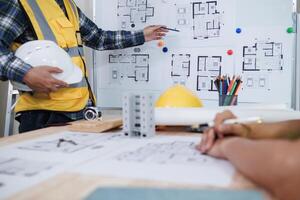 A team of engineers and architects discuss house plan design and estimate construction prices to suit the construction budget. Checking blueprints and documents with a team of engineers and architects photo