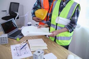 A team of engineers and architects discuss house plan design and estimate construction prices to suit the construction budget. Checking blueprints and documents with a team of engineers and architects photo