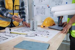 A team of engineers and architects discuss house plan design and estimate construction prices to suit the construction budget. Checking blueprints and documents with a team of engineers and architects photo
