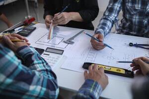 A team of engineers and architects discuss house plan design and estimate construction prices to suit the construction budget. Checking blueprints and documents with a team of engineers and architects photo