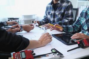 A team of engineers and architects discuss house plan design and estimate construction prices to suit the construction budget. Checking blueprints and documents with a team of engineers and architects photo