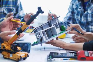 team of engineers and architects discuss house plan design and estimate construction prices to suit the construction budget. Checking blueprints and documents with a team of engineers and architects photo