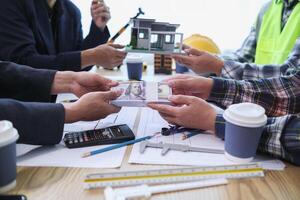team of engineers and architects discuss house plan design and estimate construction prices to suit the construction budget. Checking blueprints and documents with a team of engineers and architects photo