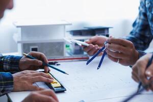 A team of engineers and architects discuss house plan design and estimate construction prices to suit the construction budget. Checking blueprints and documents with a team of engineers and architects photo