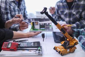 team of engineers and architects discuss house plan design and estimate construction prices to suit the construction budget. Checking blueprints and documents with a team of engineers and architects photo