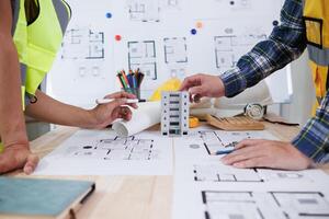 A team of engineers and architects discuss house plan design and estimate construction prices to suit the construction budget. Checking blueprints and documents with a team of engineers and architects photo