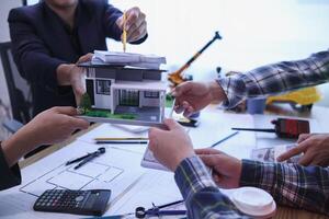 team of engineers and architects discuss house plan design and estimate construction prices to suit the construction budget. Checking blueprints and documents with a team of engineers and architects photo