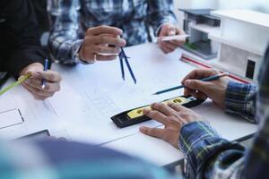 A team of engineers and architects discuss house plan design and estimate construction prices to suit the construction budget. Checking blueprints and documents with a team of engineers and architects photo