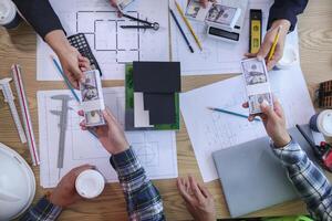 team of engineers and architects discuss house plan design and estimate construction prices to suit the construction budget. Checking blueprints and documents with a team of engineers and architects photo