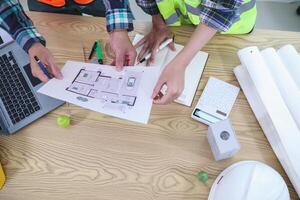 A team of engineers and architects discuss house plan design and estimate construction prices to suit the construction budget. Checking blueprints and documents with a team of engineers and architects photo