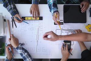 A team of engineers and architects discuss house plan design and estimate construction prices to suit the construction budget. Checking blueprints and documents with a team of engineers and architects photo