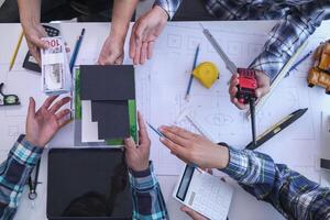 team of engineers and architects discuss house plan design and estimate construction prices to suit the construction budget. Checking blueprints and documents with a team of engineers and architects photo
