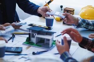 team of engineers and architects discuss house plan design and estimate construction prices to suit the construction budget. Checking blueprints and documents with a team of engineers and architects photo