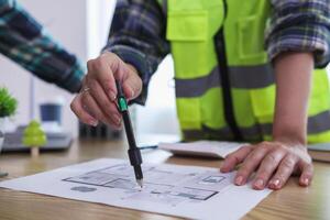 A team of engineers and architects discuss house plan design and estimate construction prices to suit the construction budget. Checking blueprints and documents with a team of engineers and architects photo