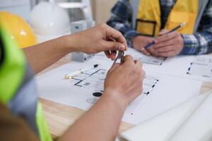 A team of engineers and architects discuss house plan design and estimate construction prices to suit the construction budget. Checking blueprints and documents with a team of engineers and architects photo