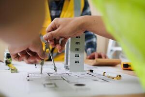 A team of engineers and architects discuss house plan design and estimate construction prices to suit the construction budget. Checking blueprints and documents with a team of engineers and architects photo