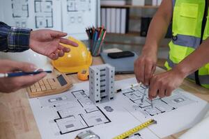 A team of engineers and architects discuss house plan design and estimate construction prices to suit the construction budget. Checking blueprints and documents with a team of engineers and architects photo