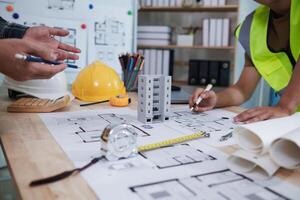A team of engineers and architects discuss house plan design and estimate construction prices to suit the construction budget. Checking blueprints and documents with a team of engineers and architects photo