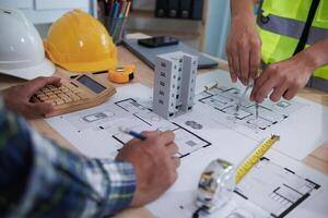 A team of engineers and architects discuss house plan design and estimate construction prices to suit the construction budget. Checking blueprints and documents with a team of engineers and architects photo