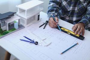 A team of engineers and architects discuss house plan design and estimate construction prices to suit the construction budget. Checking blueprints and documents with a team of engineers and architects photo