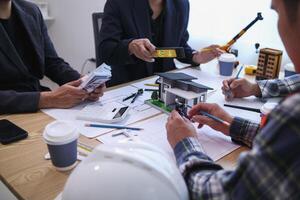 team of engineers and architects discuss house plan design and estimate construction prices to suit the construction budget. Checking blueprints and documents with a team of engineers and architects photo