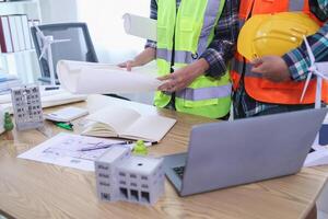 A team of engineers and architects discuss house plan design and estimate construction prices to suit the construction budget. Checking blueprints and documents with a team of engineers and architects photo