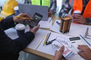 team of engineers and architects discuss house plan design and estimate construction prices to suit the construction budget. Checking blueprints and documents with a team of engineers and architects photo