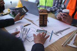 team of engineers and architects discuss house plan design and estimate construction prices to suit the construction budget. Checking blueprints and documents with a team of engineers and architects photo