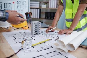 A team of engineers and architects discuss house plan design and estimate construction prices to suit the construction budget. Checking blueprints and documents with a team of engineers and architects photo