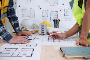 A team of engineers and architects discuss house plan design and estimate construction prices to suit the construction budget. Checking blueprints and documents with a team of engineers and architects photo