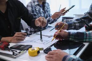 A team of engineers and architects discuss house plan design and estimate construction prices to suit the construction budget. Checking blueprints and documents with a team of engineers and architects photo