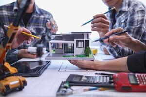 team of engineers and architects discuss house plan design and estimate construction prices to suit the construction budget. Checking blueprints and documents with a team of engineers and architects photo