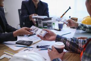 team of engineers and architects discuss house plan design and estimate construction prices to suit the construction budget. Checking blueprints and documents with a team of engineers and architects photo