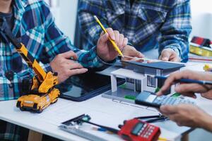 team of engineers and architects discuss house plan design and estimate construction prices to suit the construction budget. Checking blueprints and documents with a team of engineers and architects photo