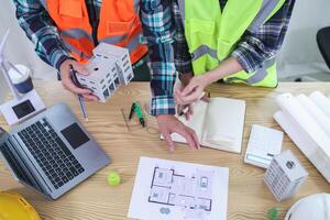 A team of engineers and architects discuss house plan design and estimate construction prices to suit the construction budget. Checking blueprints and documents with a team of engineers and architects photo