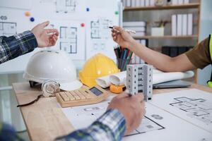 A team of engineers and architects discuss house plan design and estimate construction prices to suit the construction budget. Checking blueprints and documents with a team of engineers and architects photo