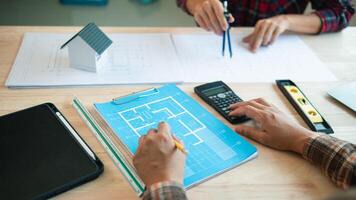 A team of engineers and architects discuss house plan design and estimate construction prices to suit the construction budget. Checking blueprints and documents with a team of engineers and architects photo
