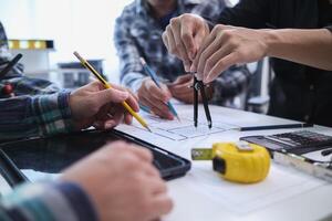 A team of engineers and architects discuss house plan design and estimate construction prices to suit the construction budget. Checking blueprints and documents with a team of engineers and architects photo
