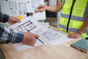 A team of engineers and architects discuss house plan design and estimate construction prices to suit the construction budget. Checking blueprints and documents with a team of engineers and architects photo