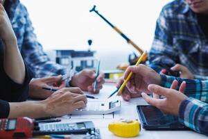 A team of engineers and architects discuss house plan design and estimate construction prices to suit the construction budget. Checking blueprints and documents with a team of engineers and architects photo