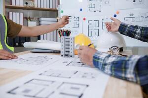 A team of engineers and architects discuss house plan design and estimate construction prices to suit the construction budget. Checking blueprints and documents with a team of engineers and architects photo