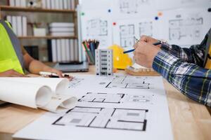A team of engineers and architects discuss house plan design and estimate construction prices to suit the construction budget. Checking blueprints and documents with a team of engineers and architects photo