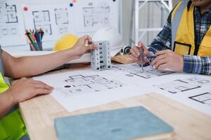 A team of engineers and architects discuss house plan design and estimate construction prices to suit the construction budget. Checking blueprints and documents with a team of engineers and architects photo